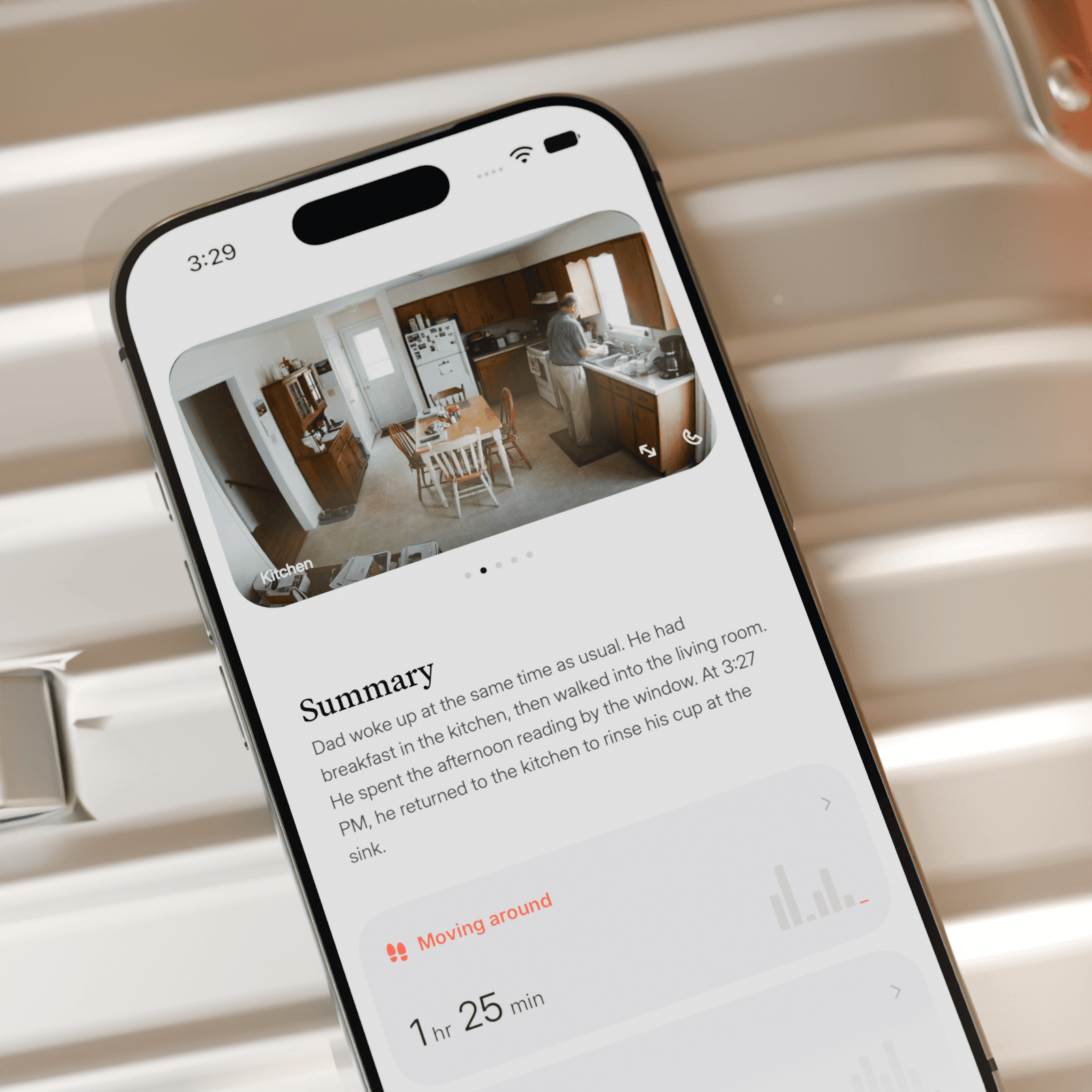 Lighthouse mobile app on a phone resting on a suitcase, showing Dad in his kitchen and a daily summary